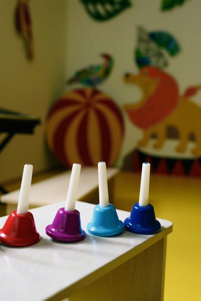 Vibrant hand bells on a table in a colorful children's room with playful wall art.